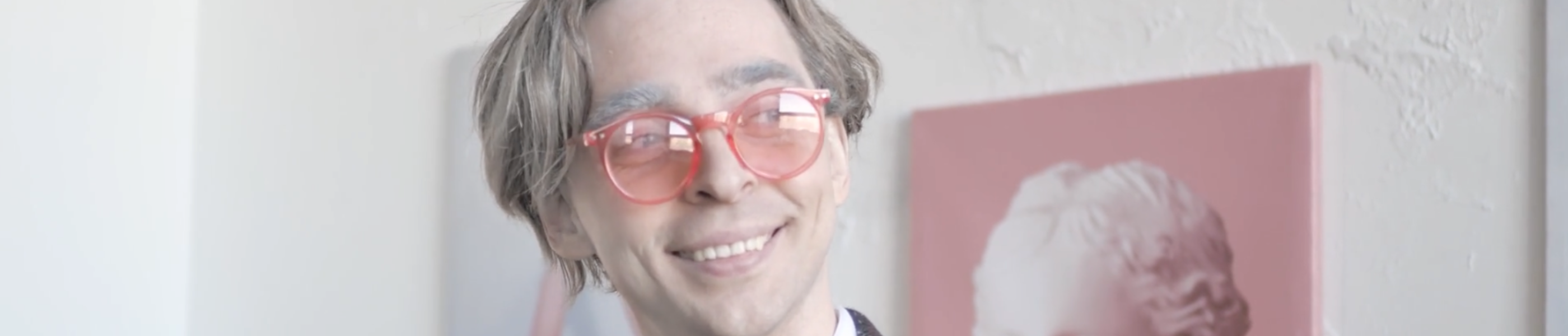 Foto van een lachende persoon met een zalmroze bril