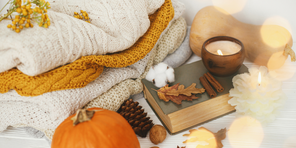 Sfeer afbeelding van de herfst met een pompoen, kleedjes, een boek, een kaars en kaneel